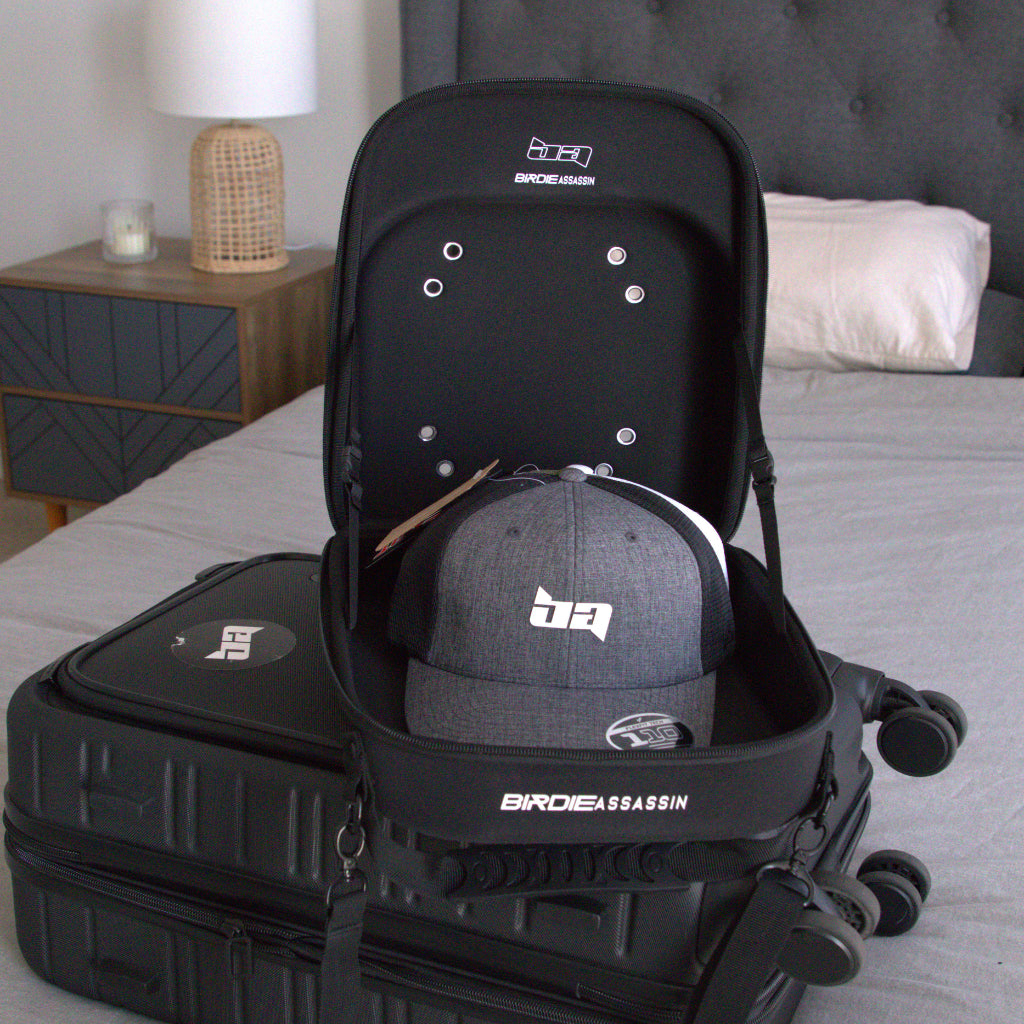 Black Birdie Assassin cap ca with a grey cap inside, placed on a bed in a bedroom 