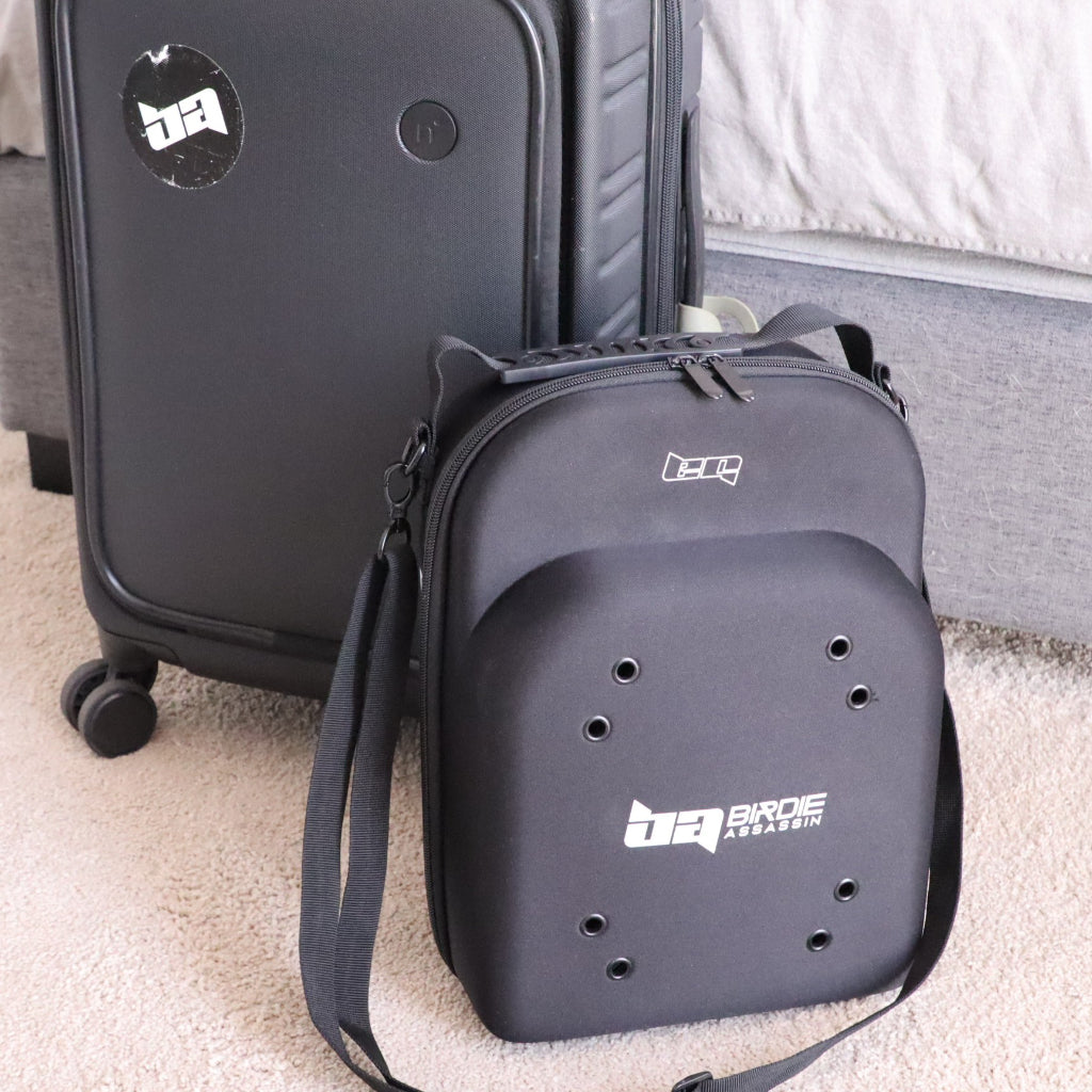 Black Birdie Assassin cap carry case siting on the ground next to a suitcase 