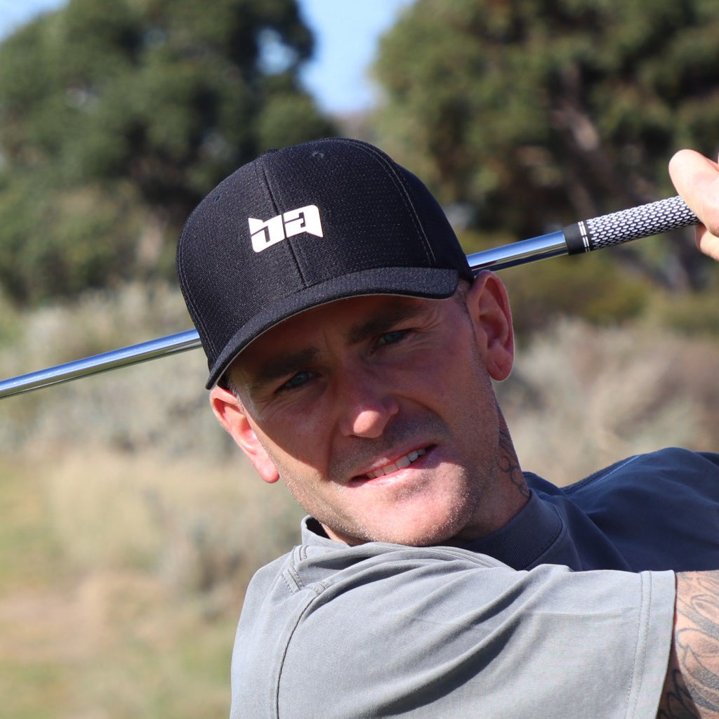 Man wearing a black Payers golf cap from Birdie Assassin holding a golf club.