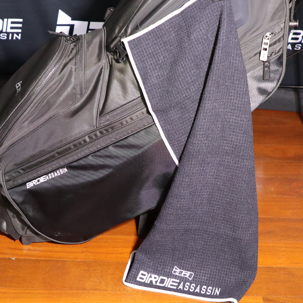 Black Birdie Assassin golf towel attached to a golf bag 