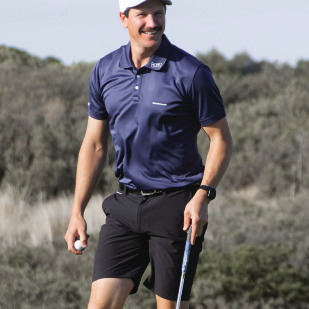 Man in a Bourne golf polo from birdie assassin smiling holding a golf ball 