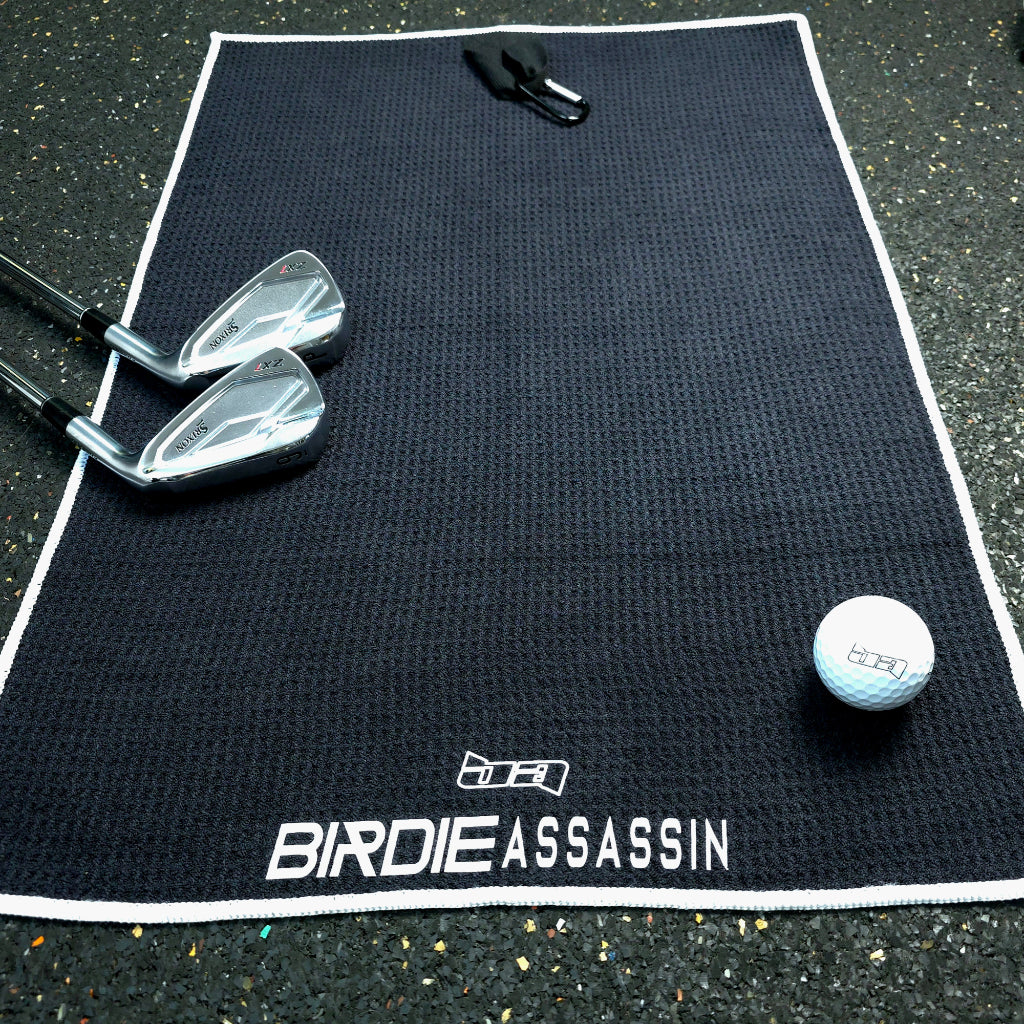 Birdie Assassin black golf towel with 2 clubs and a ball on it