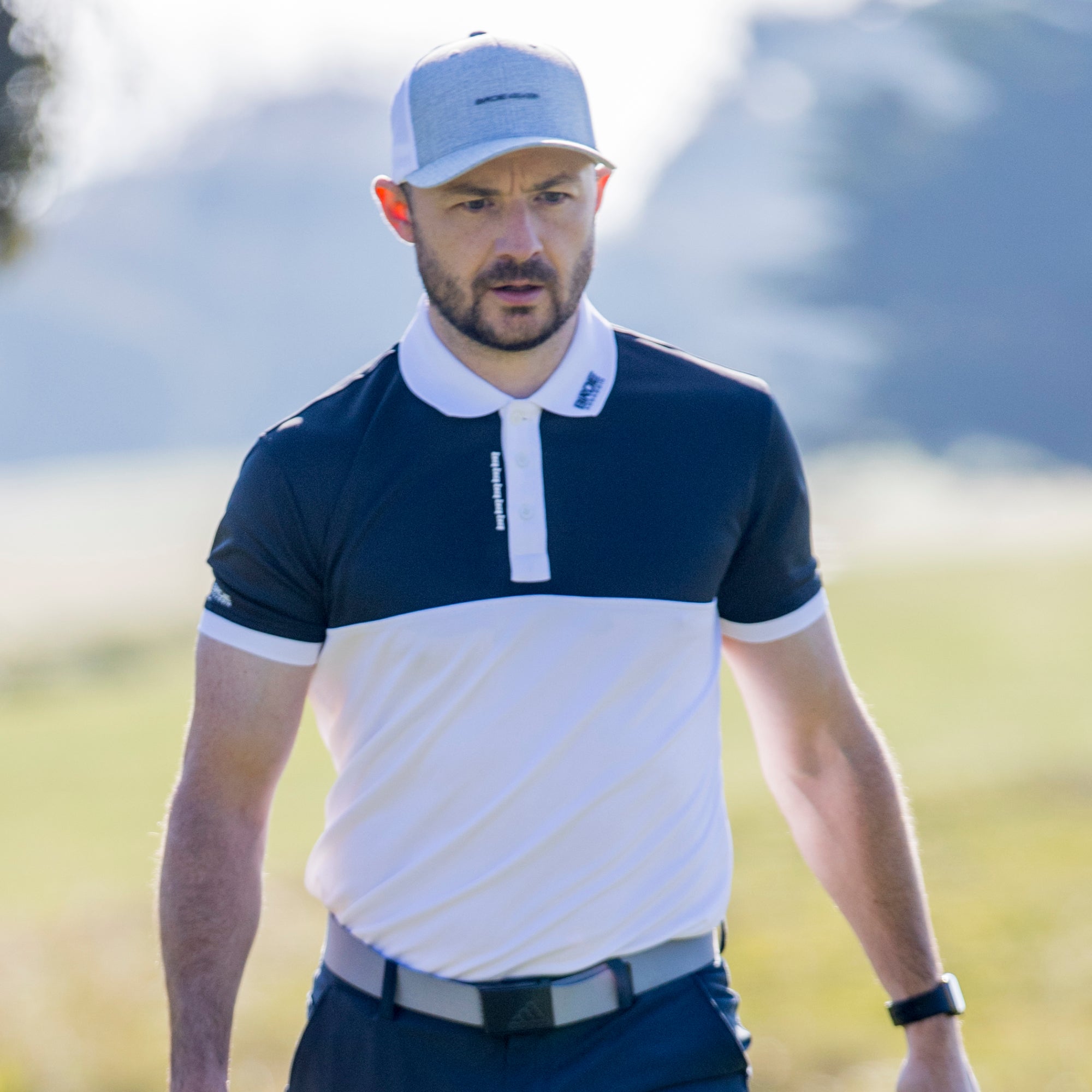Man wearing a Yakuza golf polo shirt from Birdie Assassin with a cap on a putting green