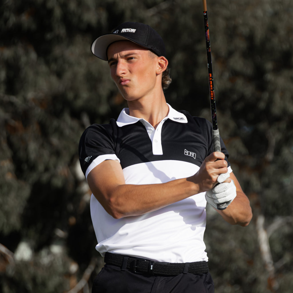 Golfer in Yakuza golf polo from Birdie Assassin holding a golf club with blurred trees in the background